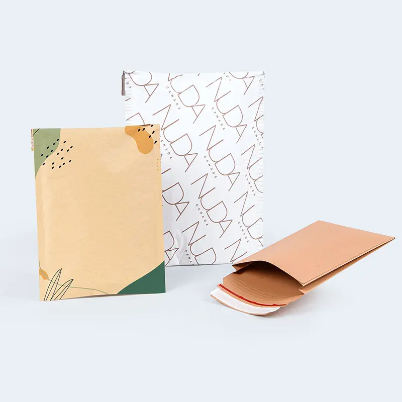 Three different paper packages are displayed on the homepage: one with abstract green and orange designs, one branded with the word "NUDA" repeated in a pattern, and one plain light brown envelope with an open flap.