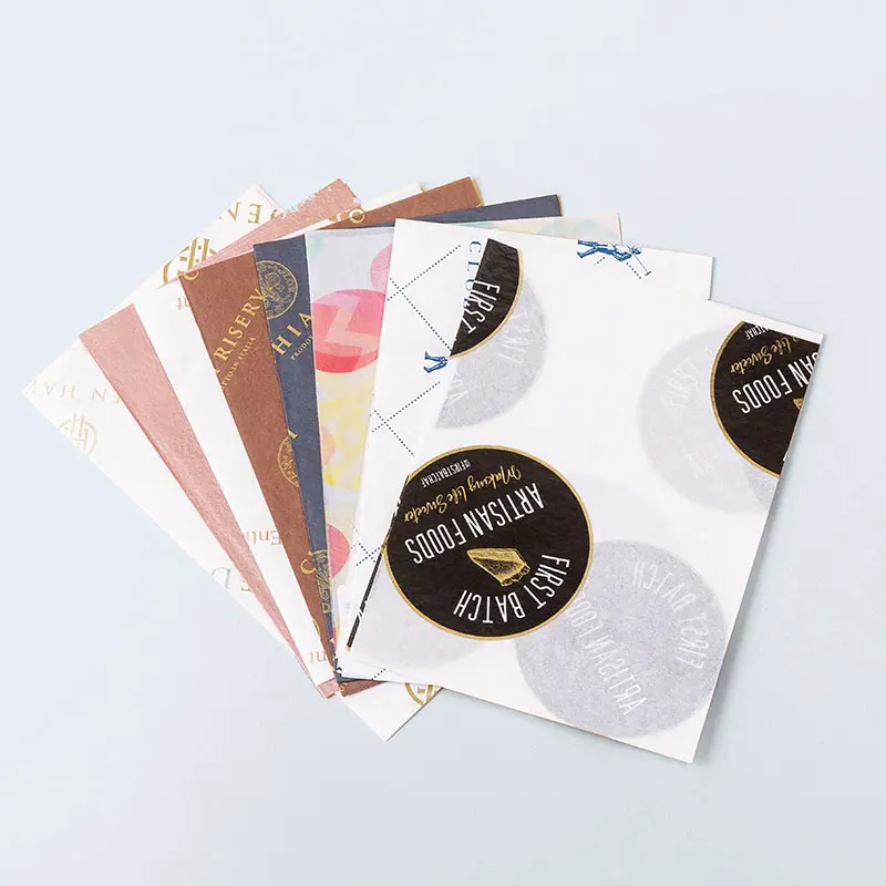 Assorted sheets of decorative paper with various designs, including circular logos, vintage elements, and pastel colors, fanned out in a charming display reminiscent of a cozy home against a light grey background.